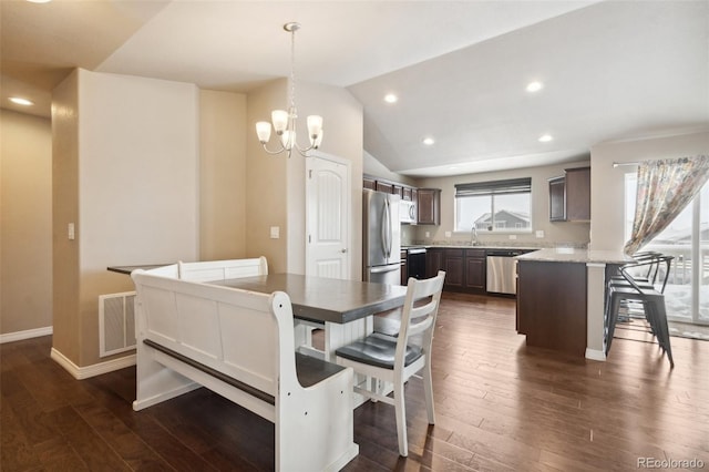 dining area with dark hardwood / wood-style flooring, sink, a chandelier, and vaulted ceiling