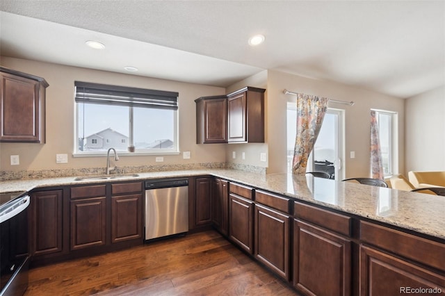 kitchen with sink, kitchen peninsula, appliances with stainless steel finishes, light stone countertops, and dark hardwood / wood-style flooring