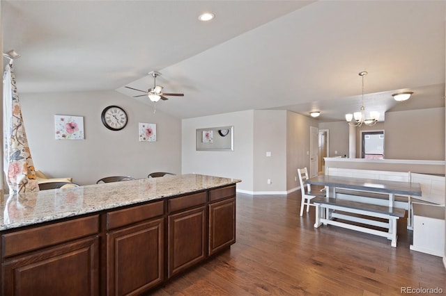 kitchen featuring ceiling fan with notable chandelier, dark hardwood / wood-style flooring, light stone counters, vaulted ceiling, and hanging light fixtures