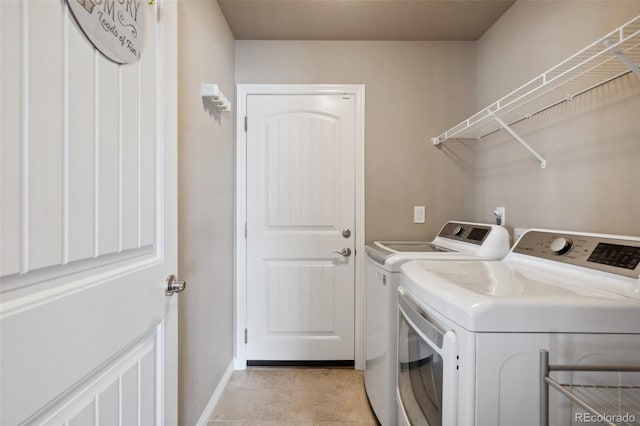 laundry area featuring washing machine and dryer and light tile patterned floors