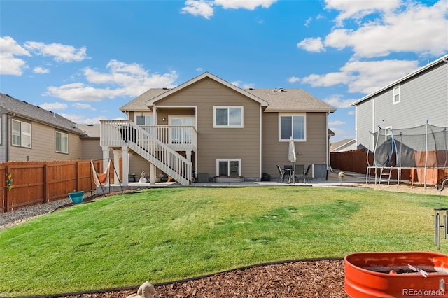 rear view of property featuring a lawn, a patio area, and a trampoline