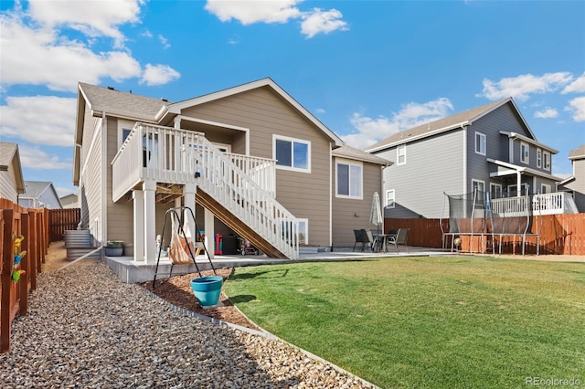 back of house with a yard, a wooden deck, and a patio