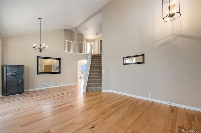 6833 E 115th Ave, Thornton, CO 80233 - unfurnished living room featuring stairway, light wood finished floors, a chandelier, and high vaulted ceiling
