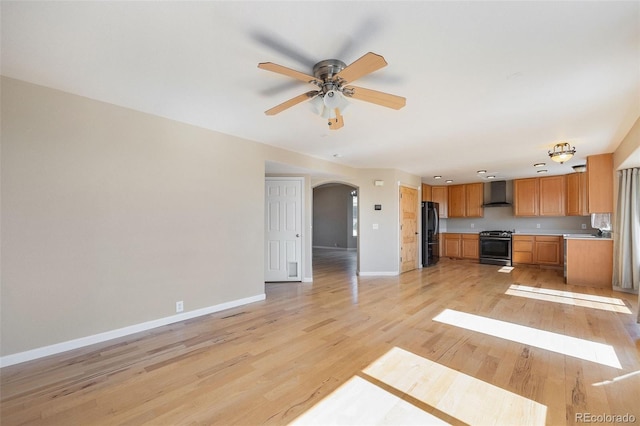 6833 E 115th Ave, Thornton, CO 80233 - kitchen with wall chimney exhaust hood, freestanding refrigerator, stainless steel range oven, arched walkways, and light wood-style flooring
