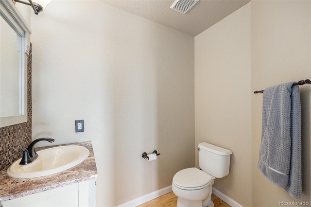 6833 E 115th Ave, Thornton, CO 80233 - half bath featuring vanity, decorative backsplash, and wood finished floors