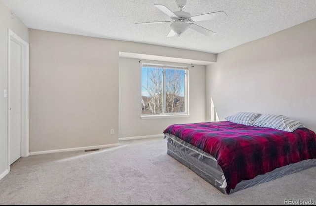 bedroom with ceiling fan, carpet, and a textured ceiling