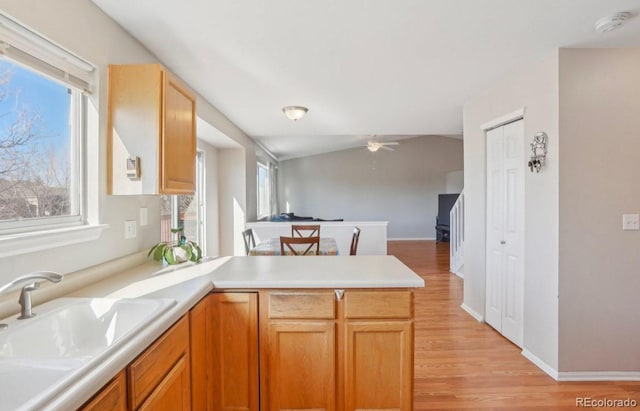 kitchen with sink, light hardwood / wood-style flooring, ceiling fan, vaulted ceiling, and kitchen peninsula