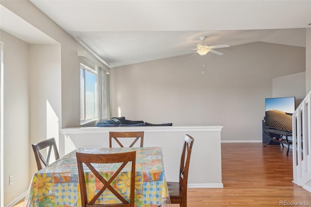 dining area featuring wood-type flooring, lofted ceiling, a textured ceiling, and ceiling fan