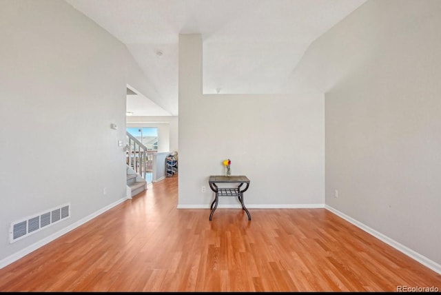 unfurnished room featuring lofted ceiling and light hardwood / wood-style flooring