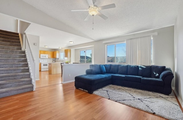 living room with ceiling fan, light hardwood / wood-style floors, and a textured ceiling