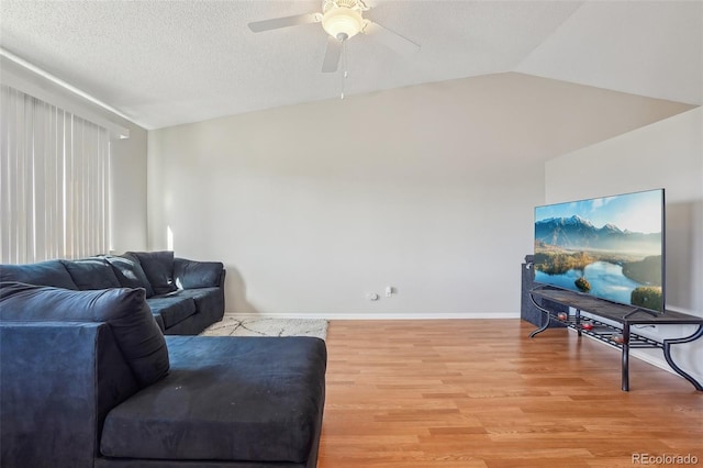 living room featuring lofted ceiling, ceiling fan, light hardwood / wood-style floors, and a textured ceiling