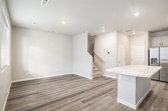 kitchen featuring stainless steel fridge with ice dispenser, a center island, and hardwood / wood-style floors