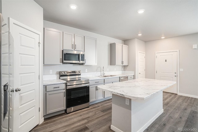 kitchen featuring gray cabinetry, sink, stainless steel appliances, dark hardwood / wood-style floors, and a kitchen island