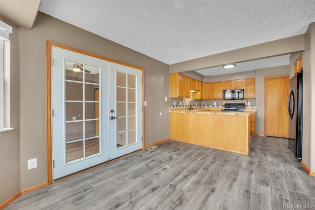 11640 Cranston Dr, Peyton, CO 80831 - kitchen with a peninsula, french doors, black appliances, light wood-type flooring, and baseboards