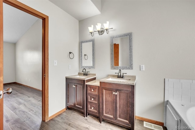 11640 Cranston Dr, Peyton, CO 80831 - bathroom with a sink, wood finished floors, visible vents, two vanities, and baseboards