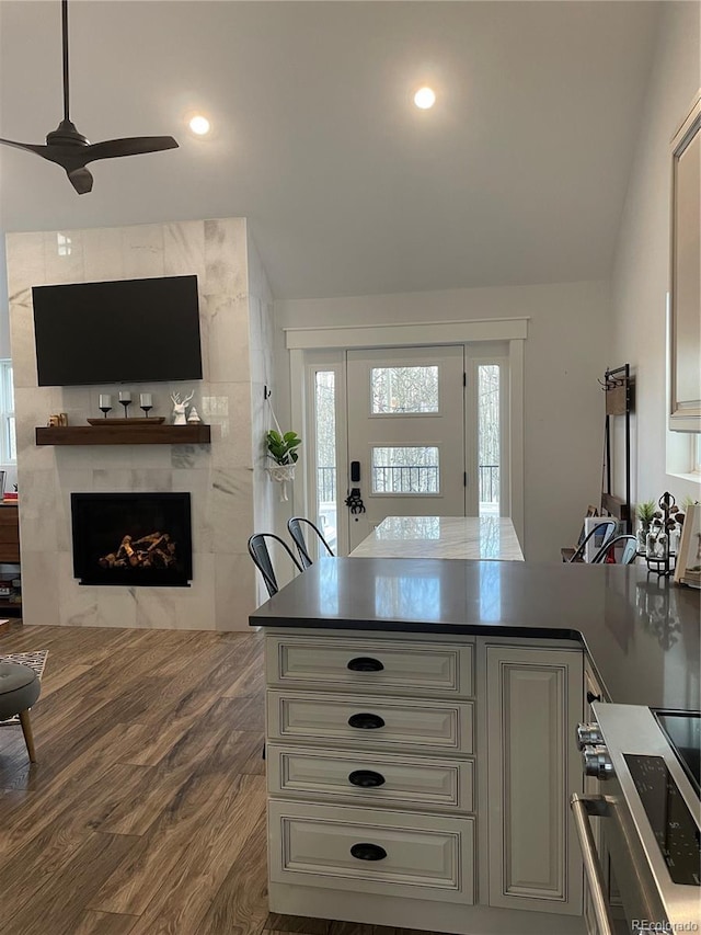 47 Lumberjack Rd, Fairplay, CO 80440 - kitchen featuring a tile fireplace, stove, ceiling fan, a peninsula, and dark wood-type flooring
