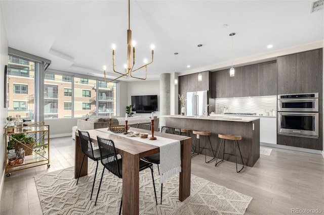 dining room featuring a chandelier, sink, and light hardwood / wood-style flooring