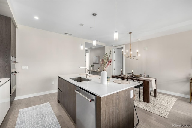 kitchen featuring sink, hanging light fixtures, a kitchen island with sink, dark brown cabinetry, and stainless steel appliances