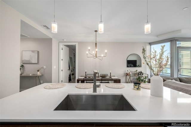 kitchen with a kitchen island, sink, a chandelier, and decorative light fixtures