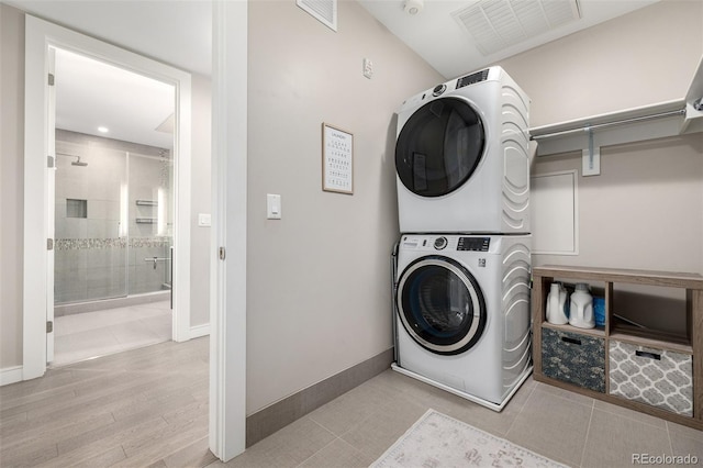 clothes washing area with stacked washer and clothes dryer and light hardwood / wood-style flooring