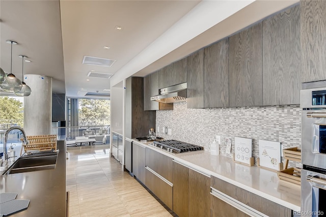 kitchen featuring sink, appliances with stainless steel finishes, floor to ceiling windows, tasteful backsplash, and decorative light fixtures