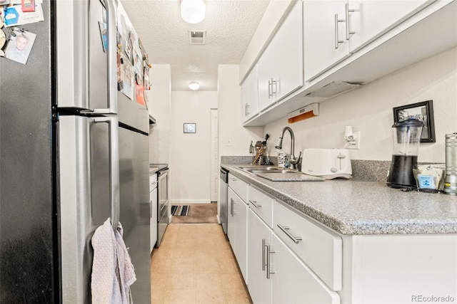 kitchen with a textured ceiling, appliances with stainless steel finishes, sink, and white cabinets