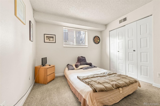 carpeted bedroom with a textured ceiling and a closet