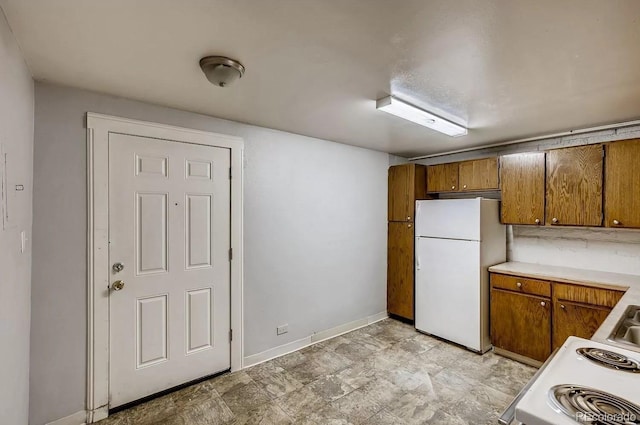 141 Mcclure Ave, Firestone, CO 80520 - kitchen with white appliances, brown cabinetry, light countertops, and baseboards