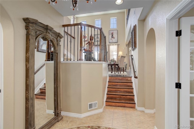 9546 Firenze Way, Highlands Ranch, CO 80126 - entrance foyer featuring stairs, arched walkways, a chandelier, tile patterned floors, and baseboards
