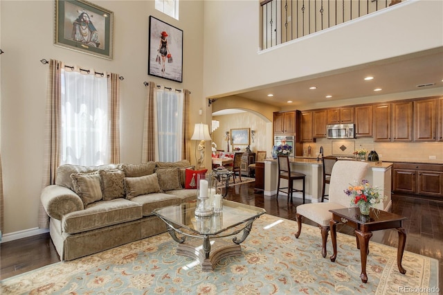 9546 Firenze Way, Highlands Ranch, CO 80126 - living area featuring arched walkways, plenty of natural light, dark wood-type flooring, a towering ceiling, and recessed lighting