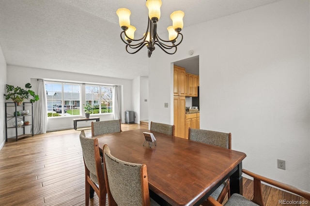 dining area with baseboards, light wood-type flooring, and a notable chandelier