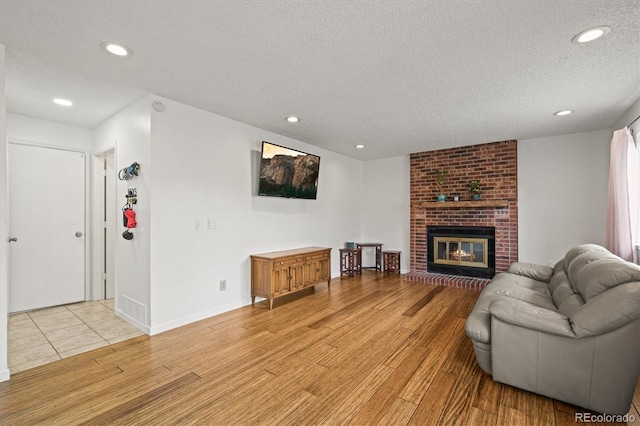 living area with recessed lighting, light wood finished floors, a textured ceiling, and visible vents