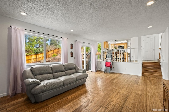 living area with recessed lighting, a textured ceiling, wood finished floors, and stairway