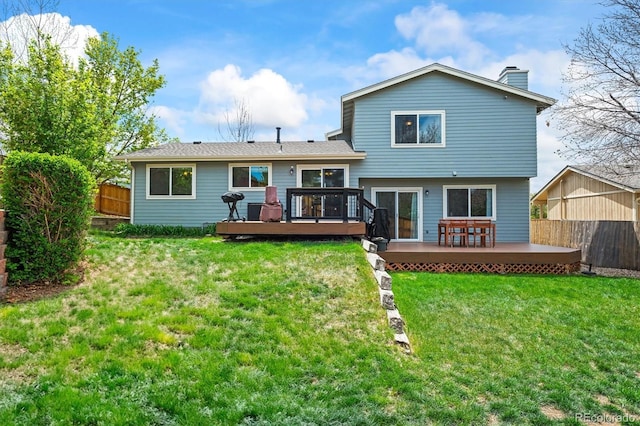 back of property with a fenced backyard, a wooden deck, and a chimney