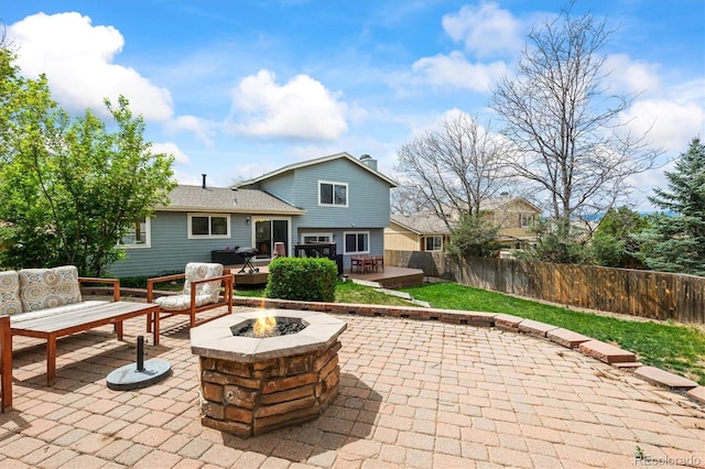 back of property with fence, an outdoor living space with a fire pit, a patio, and a wooden deck