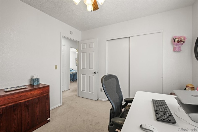 office with a textured ceiling, ceiling fan, and light carpet