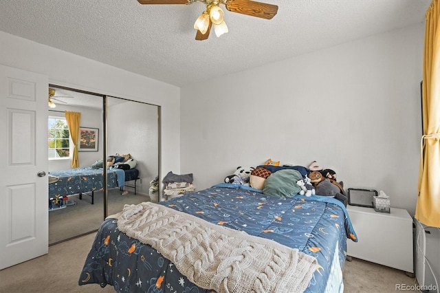 carpeted bedroom featuring a ceiling fan, a closet, and a textured ceiling