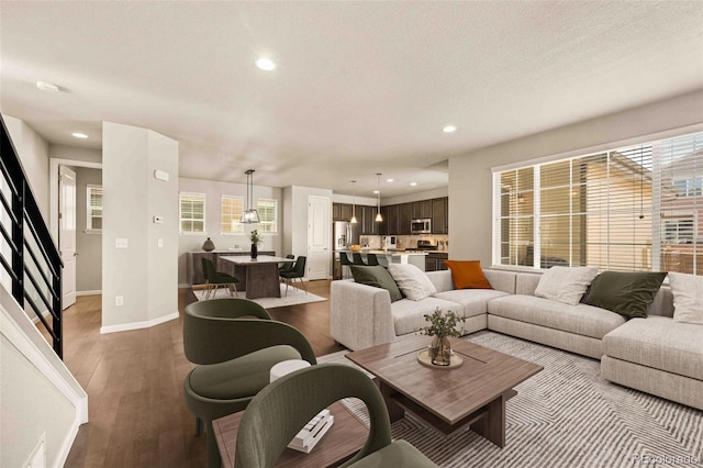 living room featuring baseboards, a textured ceiling, wood finished floors, and recessed lighting