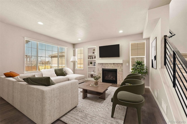 living room featuring a textured ceiling, dark wood-style flooring, and built in features