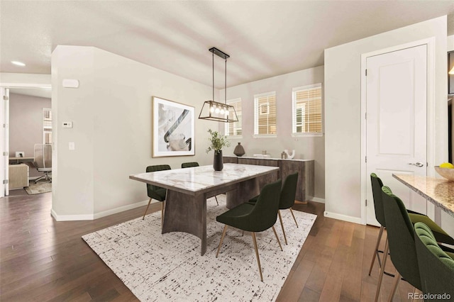 dining area featuring a chandelier, radiator heating unit, dark wood-style flooring, and baseboards