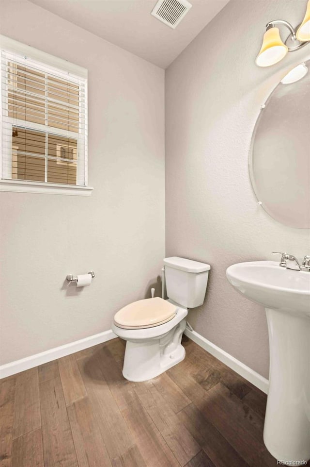 bathroom featuring baseboards, visible vents, toilet, and wood finished floors