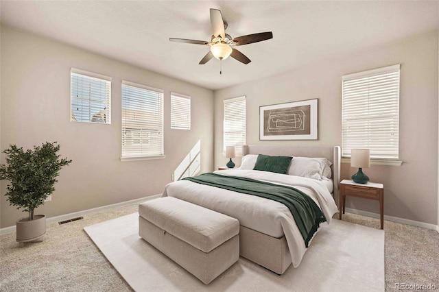 bedroom with a ceiling fan, light colored carpet, visible vents, and baseboards