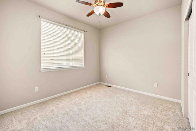 carpeted spare room with baseboards and a ceiling fan