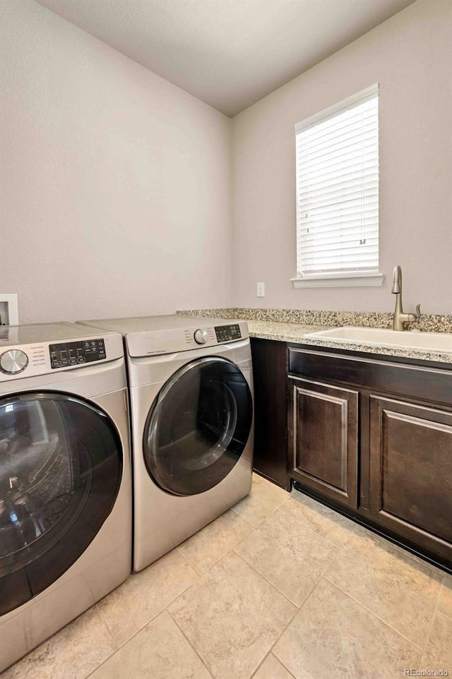 washroom with light tile patterned floors, washing machine and clothes dryer, a sink, and cabinet space