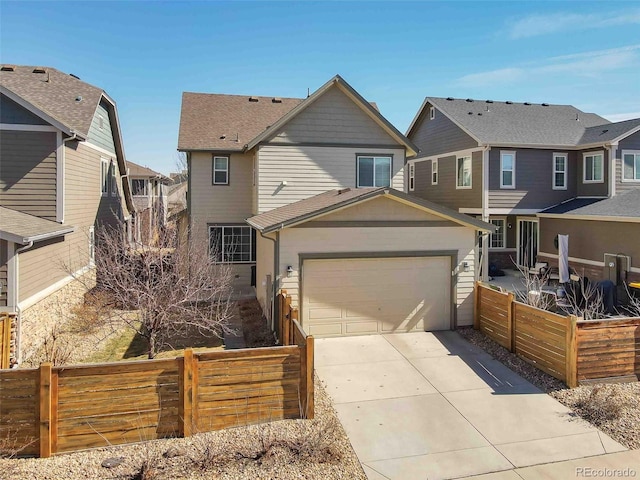 view of front of house with driveway, an attached garage, fence, and a residential view