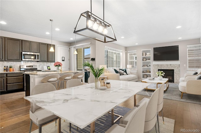 dining room with recessed lighting, light wood finished floors, a fireplace, and built in features