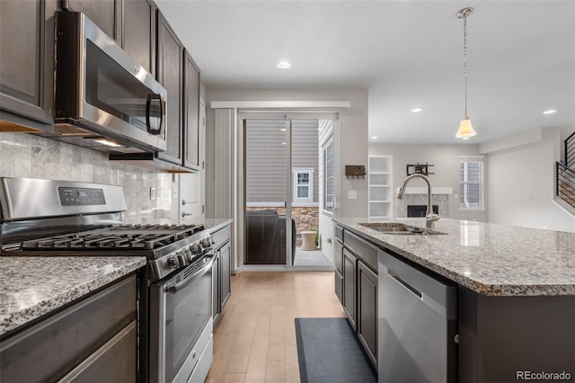 kitchen featuring tasteful backsplash, dark brown cabinetry, light wood-style floors, appliances with stainless steel finishes, and a sink