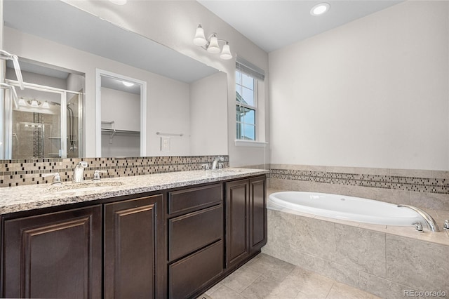 full bath with tile patterned floors, a sink, tasteful backsplash, a garden tub, and a stall shower