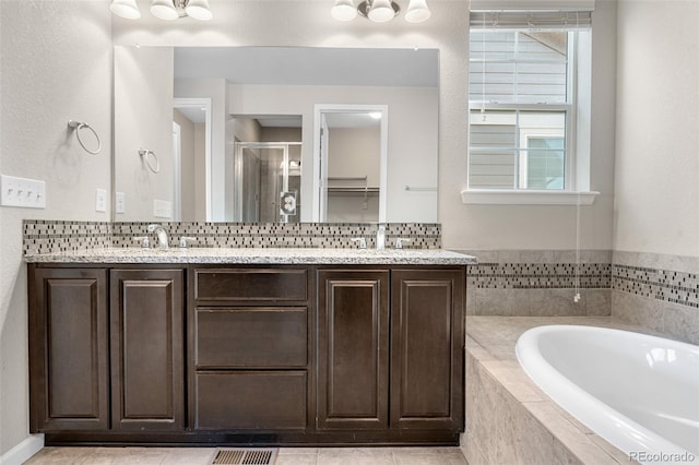 full bathroom featuring a bath, a sink, a shower stall, double vanity, and backsplash