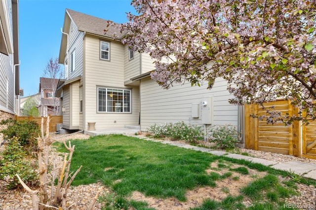 rear view of property featuring fence and a yard